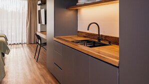 A modern kitchen with a wooden countertop, dark cabinets, and a built-in stove. - Vistalba Hotel  Aparts & Suites (Luján de Cuyo)