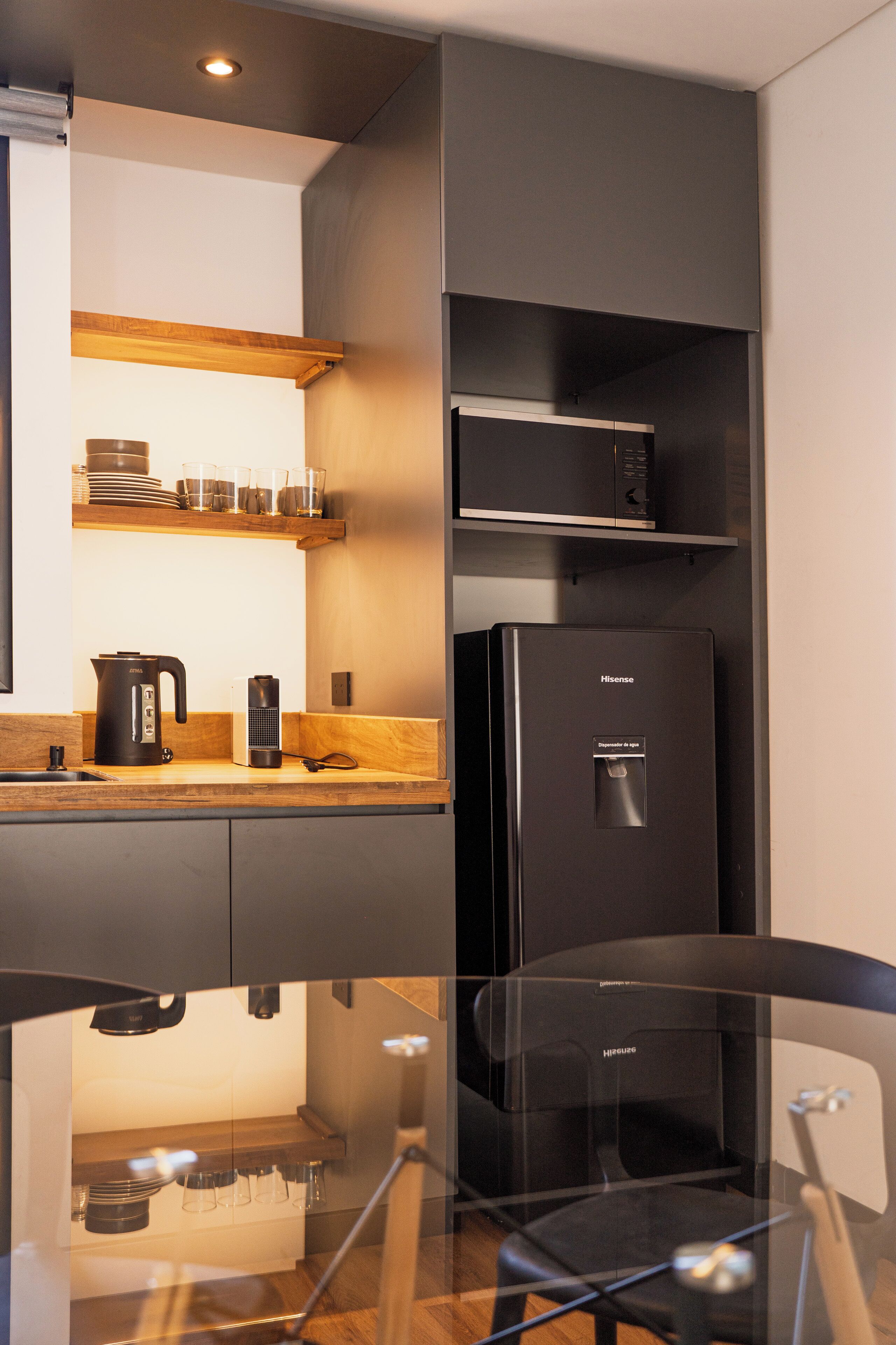 A modern kitchen with a black refrigerator, a coffee maker, and a kettle on the counter.