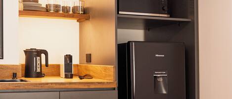 A modern kitchen with a black refrigerator, a coffee maker, and a kettle on the counter.