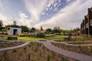 A landscaped courtyard with pathways, a small building, and modern architecture.
