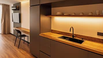 A modern kitchen with a wooden countertop, built-in appliances, and a shelf with dishes.
