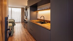 A modern kitchen with a wooden countertop, a sink, and a shelf above it. There is a chair and a bed visible in the background. - Vistalba Hotel  Aparts & Suites (Luján de Cuyo)