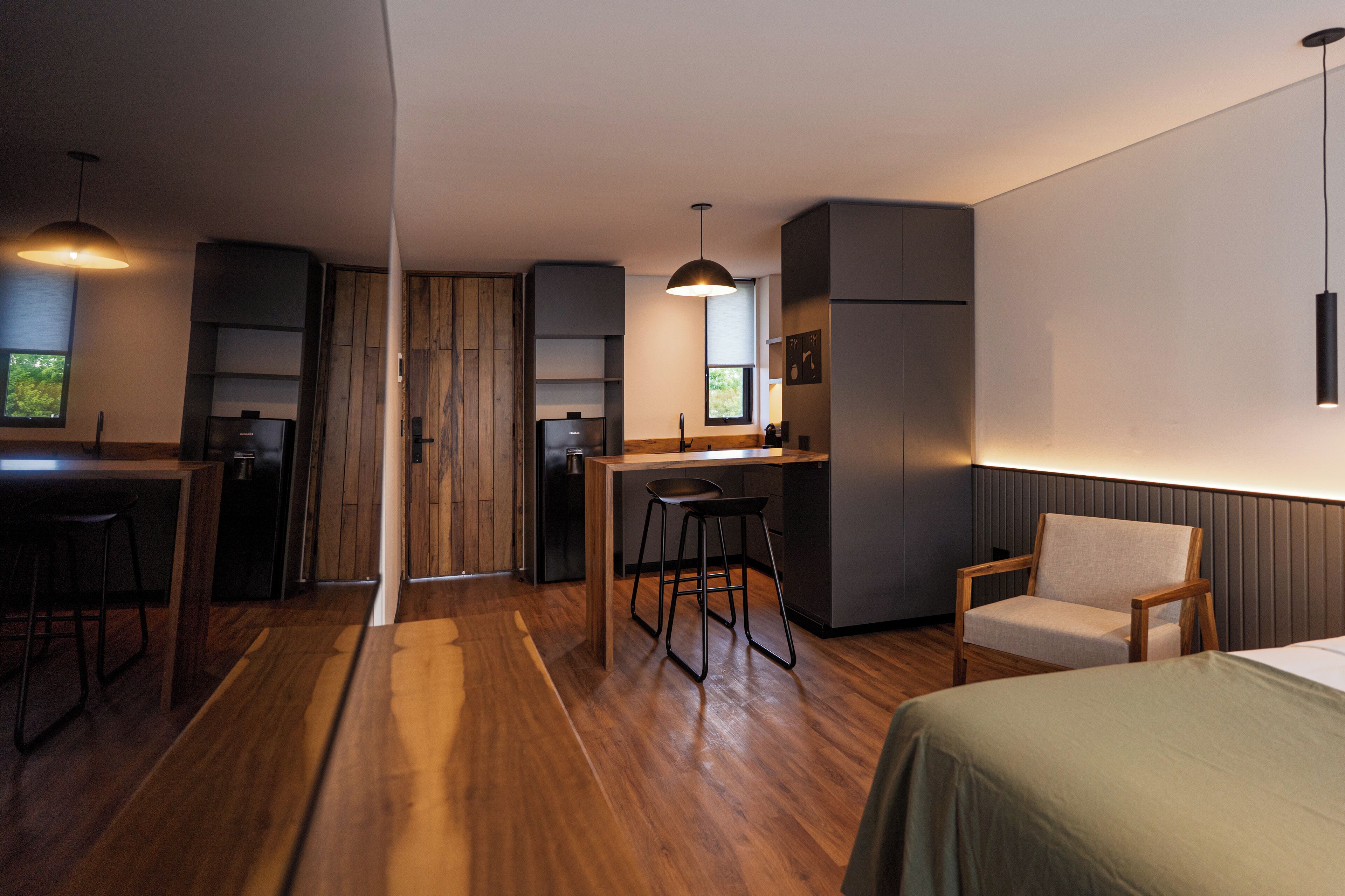A modern kitchen with wooden cabinets, a dining area with stools, and a bar area with a high chair.