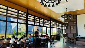 A spacious indoor dining area with large windows, modern furniture, and a central chandelier. - Nature Resort Vangvieng (Vang Vieng)