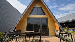 A modern A-frame building with a large glass door and a wooden deck with outdoor seating. - Nature Resort Vangvieng (Vang Vieng)