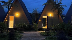 A row of triangular-shaped cabins with open doors, surrounded by lush greenery. - Nature Resort Vangvieng (Vang Vieng)