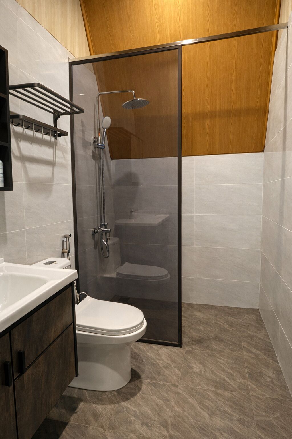 Un baño moderno con ducha de vidrio, inodoro blanco y tocador con espejo.
