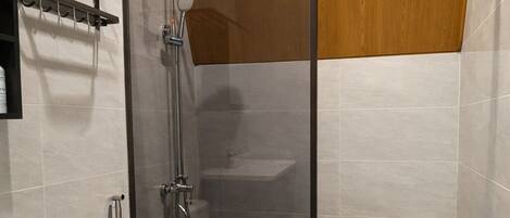 Un baño moderno con ducha de vidrio, inodoro blanco y tocador con espejo.
