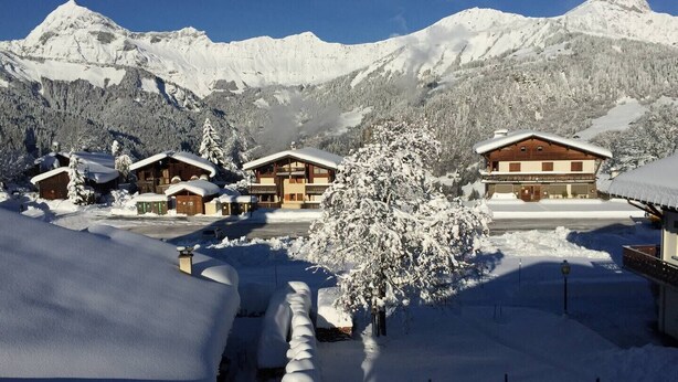 A snow-covered mountain resort with chalet-style buildings, a clear sky, and a forested backdrop. - Alpine stay at the foot of the slopes (Crest-Voland)