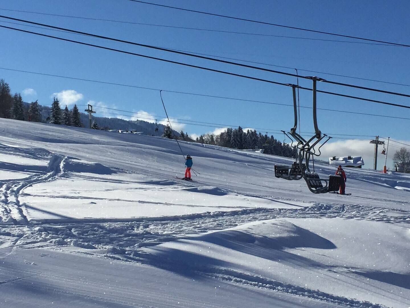 A ski slope with a ski lift and tracks in the snow.
