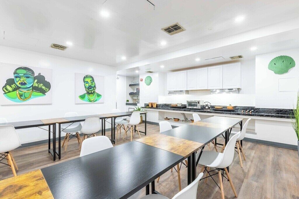 Une cuisine moderne avec des meubles blancs, un plan de travail noir et un coin repas comprenant une longue table et des chaises.