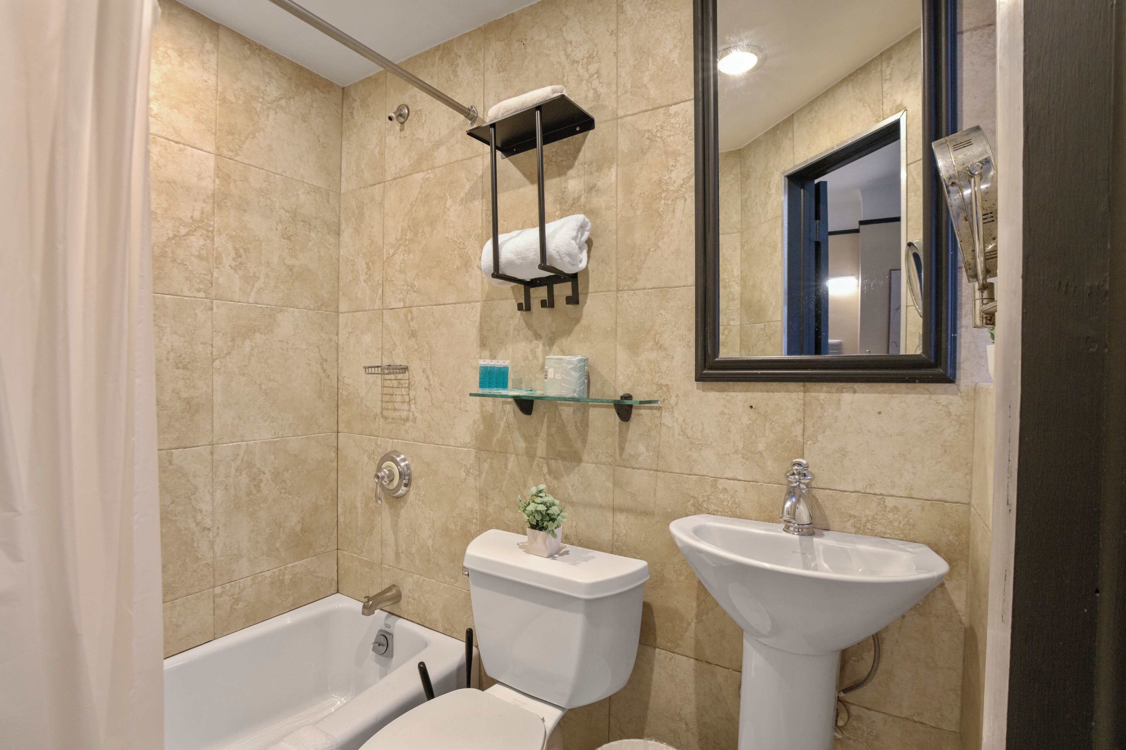 Een badkamer met een bad, toilet, wastafel en spiegel.