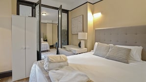 A hotel room with a bed, bedside table, lamp, and a wardrobe. - Stylish 2BR at the Historic Mansfield Residence (New York)