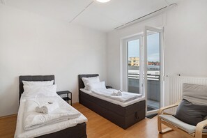 A room with two beds, a chair, and a view through a sliding door.