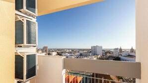 A balcony with a view of a cityscape, including buildings and a clear sky. - Margotia Apartment, Faro, Algarve (Faro)
