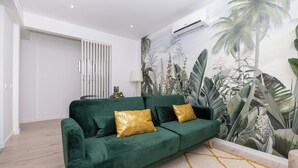 A modern living room with a green sofa, gold cushions, a white floor, and a tropical mural on the wall. - Margotia Apartment, Faro, Algarve (Faro)