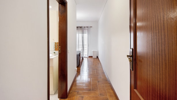 A hallway with a wooden door, a white wall, and a tiled floor. - Barra Sol - Farol na Praia Apartment with Shared Pool, Balcony, and Wi-Fi (Praia da Barra)