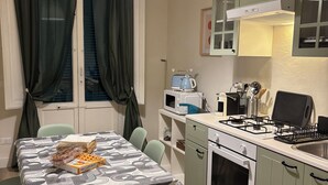 Una cocina compacta con una mesa de comedor, sillas, un microondas, una estufa y un lavabo.