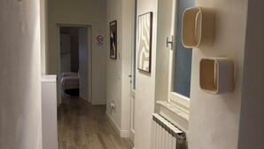 Un pasillo con suelo de madera, un radiador e iluminación empotrada en la pared.
