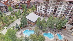 Un resort con varias piscinas, un porche cubierto y montañas al fondo.