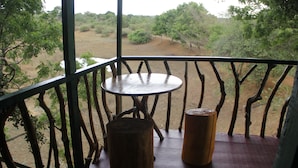 Una mesa de madera con una silla en un balcón con vista a un paisaje natural.