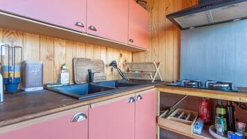 Een kleine keuken met roze kastjes, een spoelbak en een fornuis.