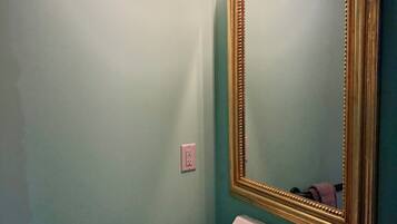A bathroom with a white sink, a gold-framed mirror, and a towel hanging on a rack.
