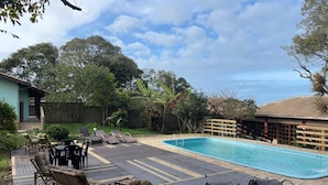 A pool area with lounge chairs and a wooden deck. - Pousada Recanto Do Costão (Florianópolis)