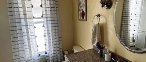 A bathroom with a toilet, sink, and shower curtain.