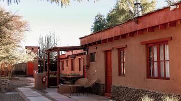A rustic building with a red roof, a covered patio, and a gravel pathway leading to the entrance.