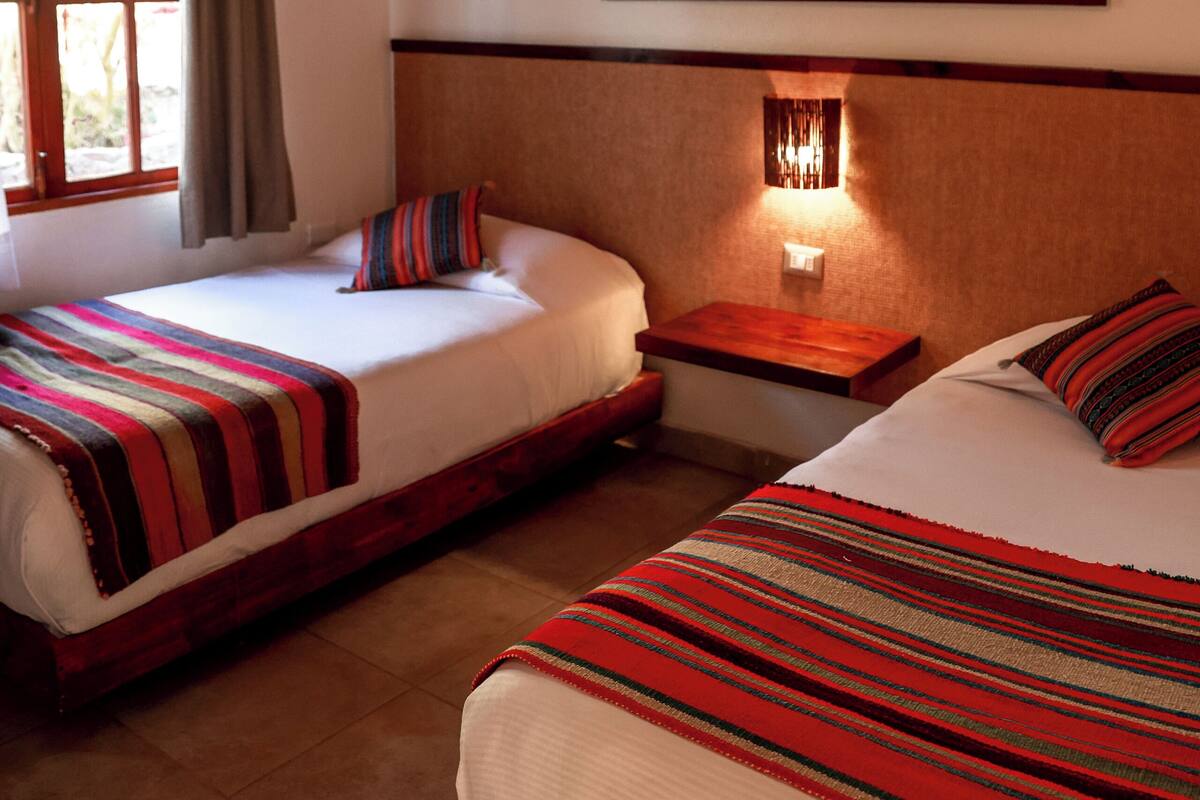 Una habitación de hotel con dos camas, un cuadro de caballos, una ventana con cortinas y un techo de madera.