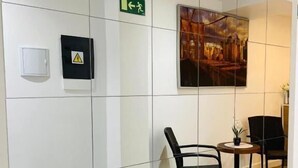 A modern interior with a glass partition, a framed picture, a chair, a small table, and a potted plant. - AS ROOMS Alicante  (Alicante)