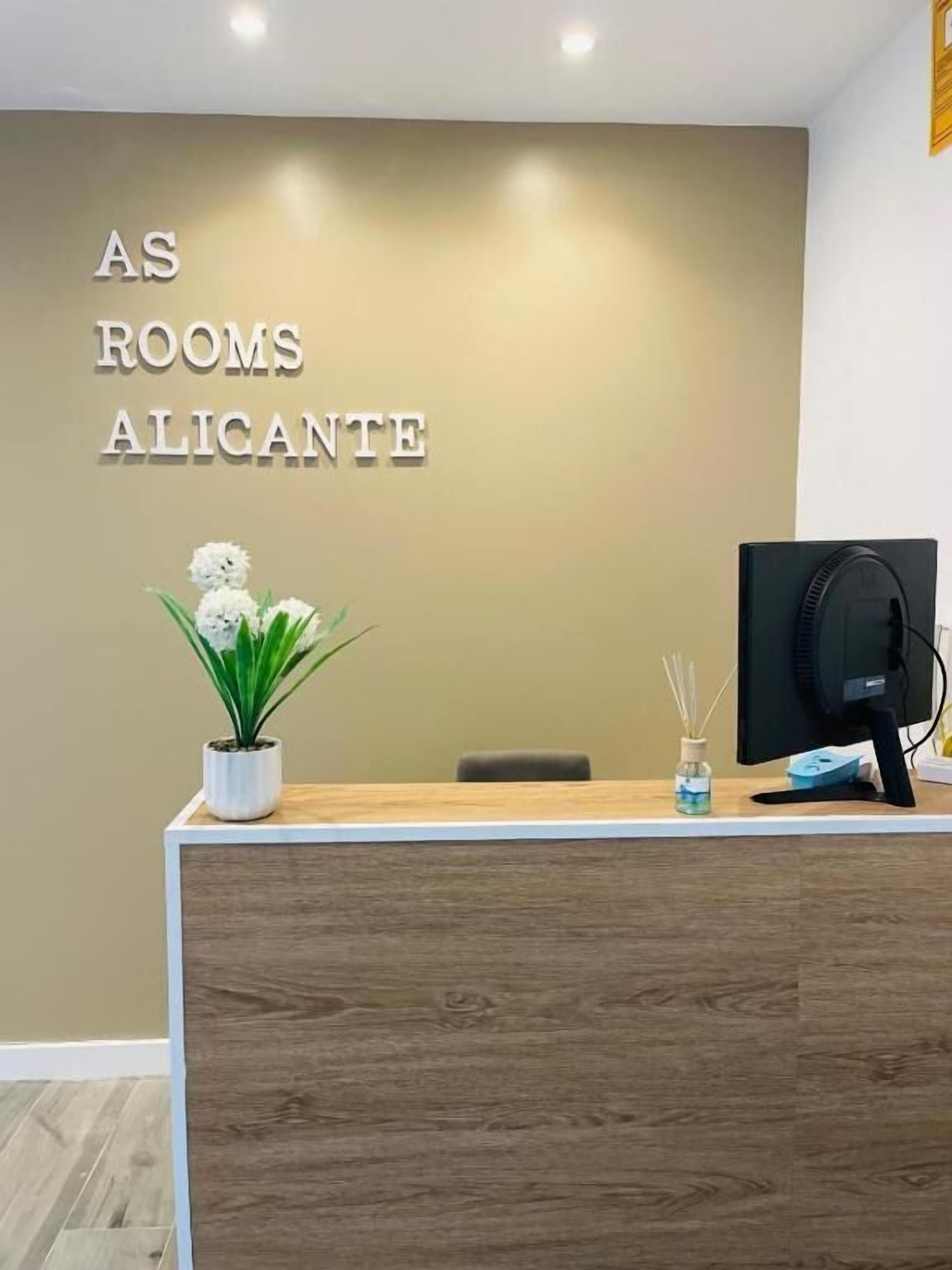 Una recepción con un cartel que dice "AS ROOMS ALICANTE" en el vestíbulo de un hotel.