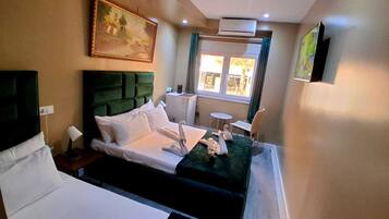 Habitación de hotel con cama, una mesita, una silla, un cuadro en la pared y una ventana con cortinas.