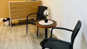 A reception area with a wooden reception desk, two black chairs, a small round table with a vase of flowers, and a large framed picture of a bridge on the wall. - AS ROOMS Alicante  (Alicante)