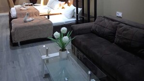 A modern hotel room with a bed, two sofas, a glass coffee table, and a small plant. - AS ROOMS Alicante  (Alicante)