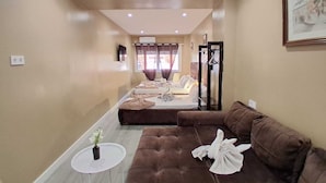 A hotel room with a brown sofa, a small round table, and a bed with towels and a robe. - AS ROOMS Alicante  (Alicante)