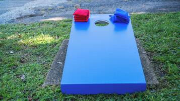 A blue board game with a hole in the center, placed on grass.