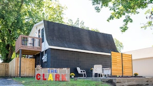 A building with a dark exterior, a wooden deck, and a sign reading "THE CLARK". - The Clark: Where Superheroes Sleep! (Metropolis)