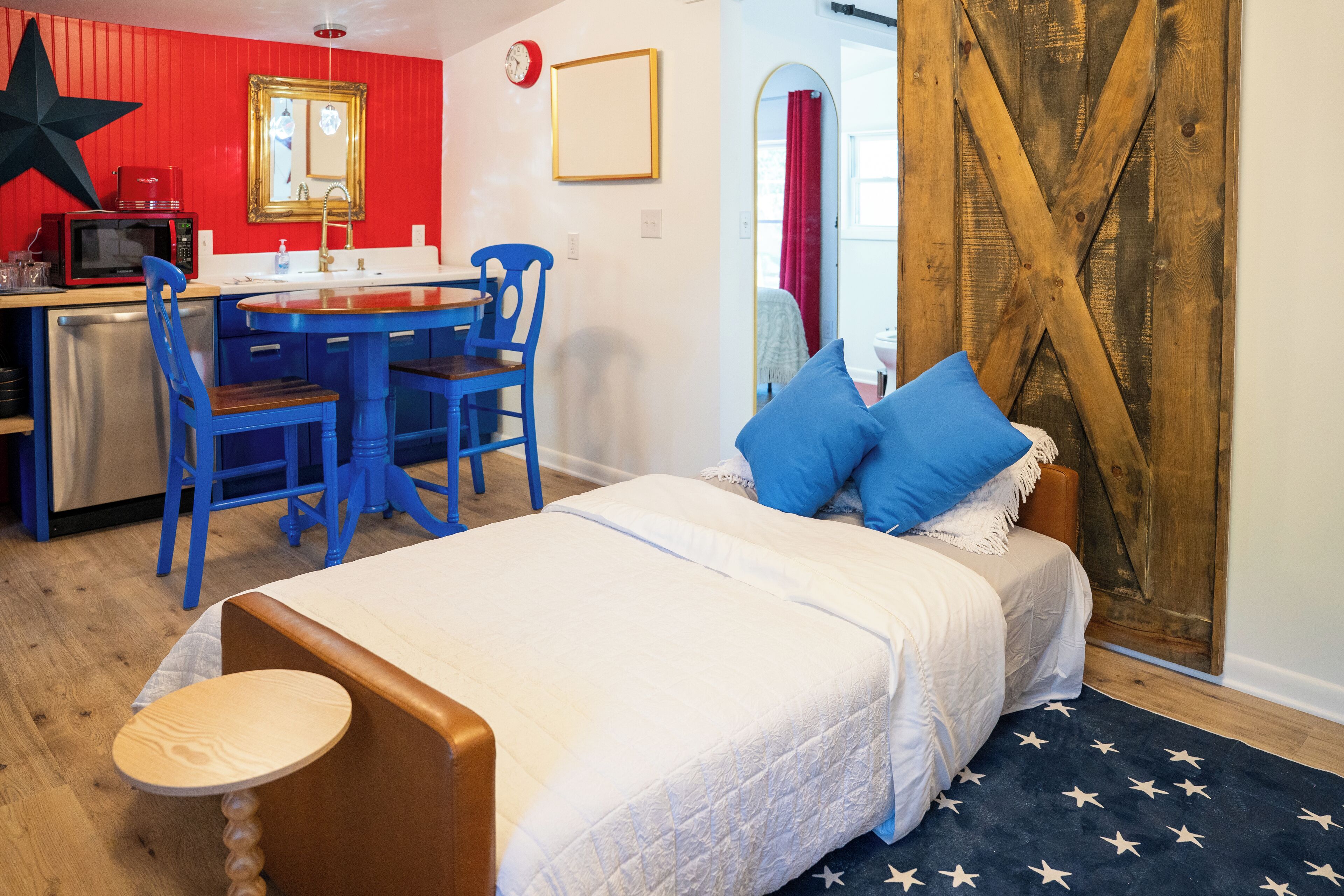 Una habitación con una cama, un escritorio con una silla, un microondas y una pared roja.