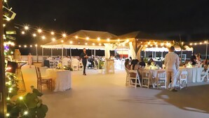 An outdoor event space with tables and chairs, string lights, and a tent.