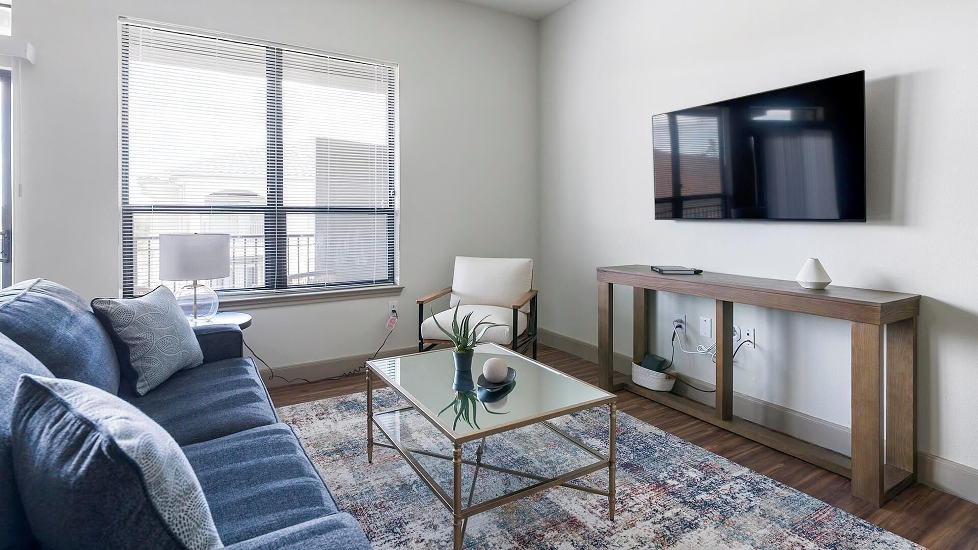 A modern living room with a sofa, coffee table, and a TV mounted on the wall.