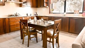 A kitchen with wooden cabinets, a dining table with chairs, and a window with a view of trees. - 7 MEDITERRANEA VILLA (St. Paul's Bay)