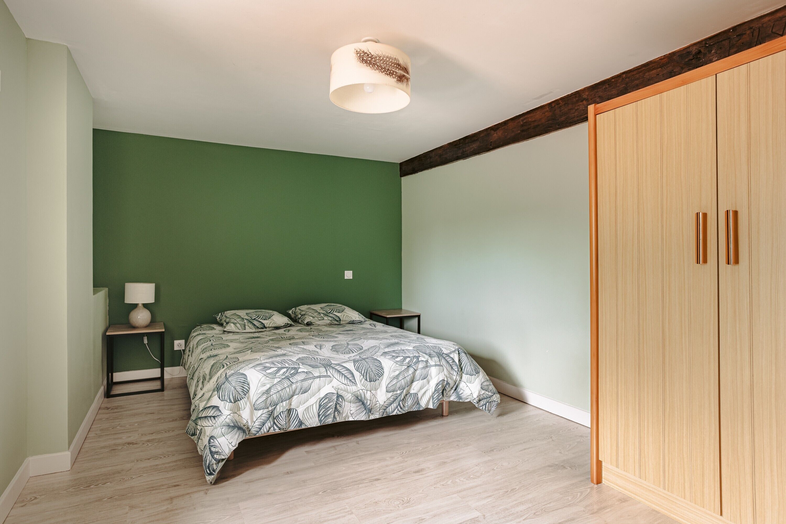 A bedroom with a bed, a nightstand, a lamp, and a wardrobe.
