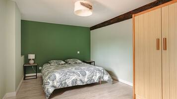 A bedroom with a bed, a nightstand, a lamp, and a wardrobe.
