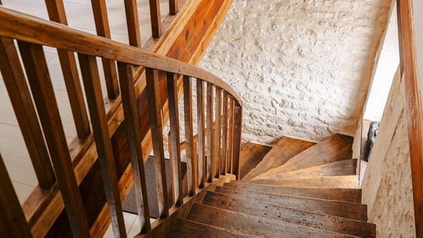 Una escalera de madera junto a una pared de piedra.