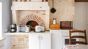 Una cocina con chimenea de ladrillo, microondas, hervidor y cafetera sobre el mostrador.