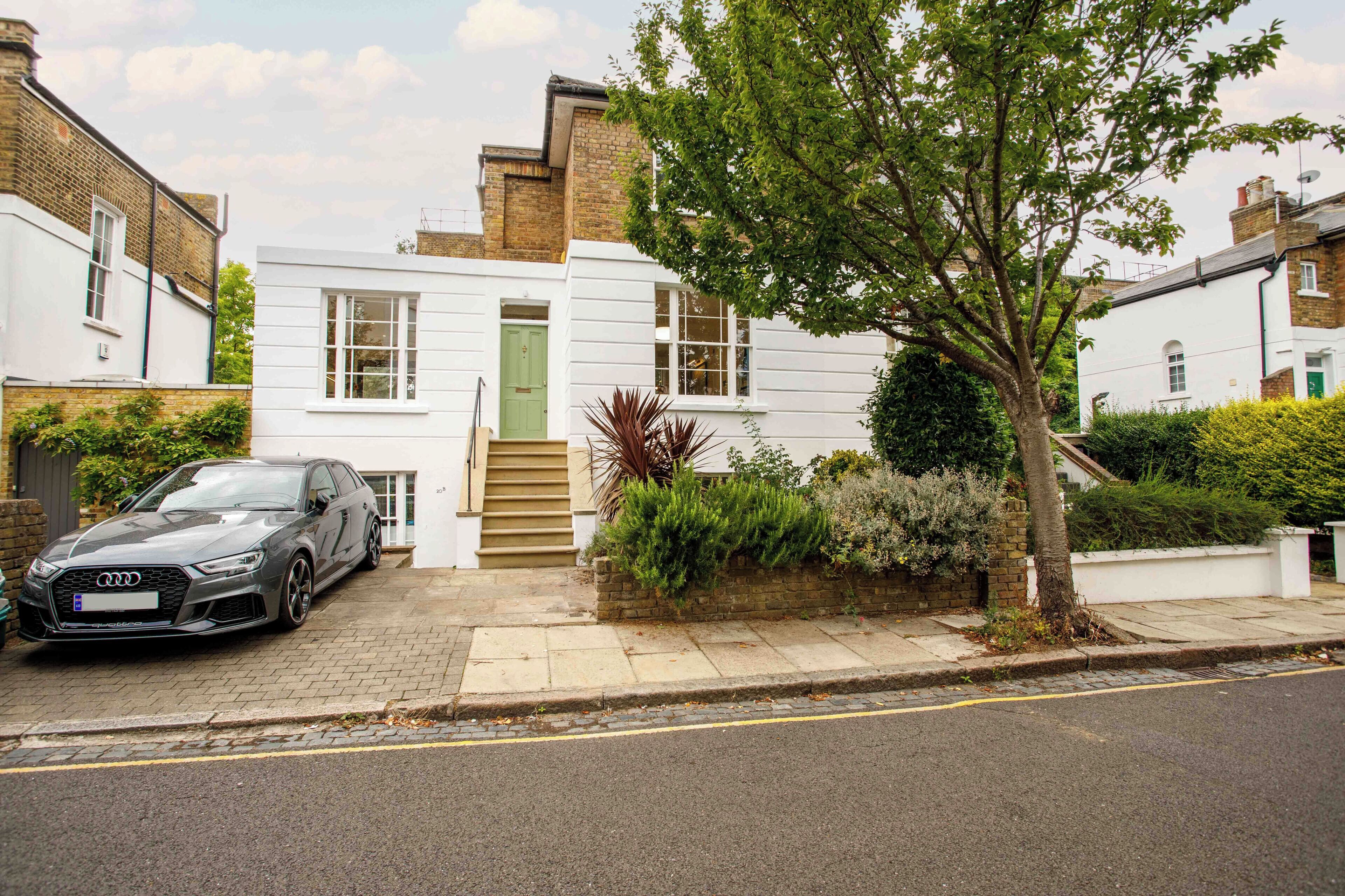 Une maison moderne à deux étages, avec une voiture garée dans l’allée.
