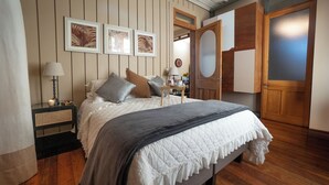 A bedroom with a bed, bedside table, lamp, and framed artwork on the wall. - Departamentos Puerto Claro (Valparaíso)