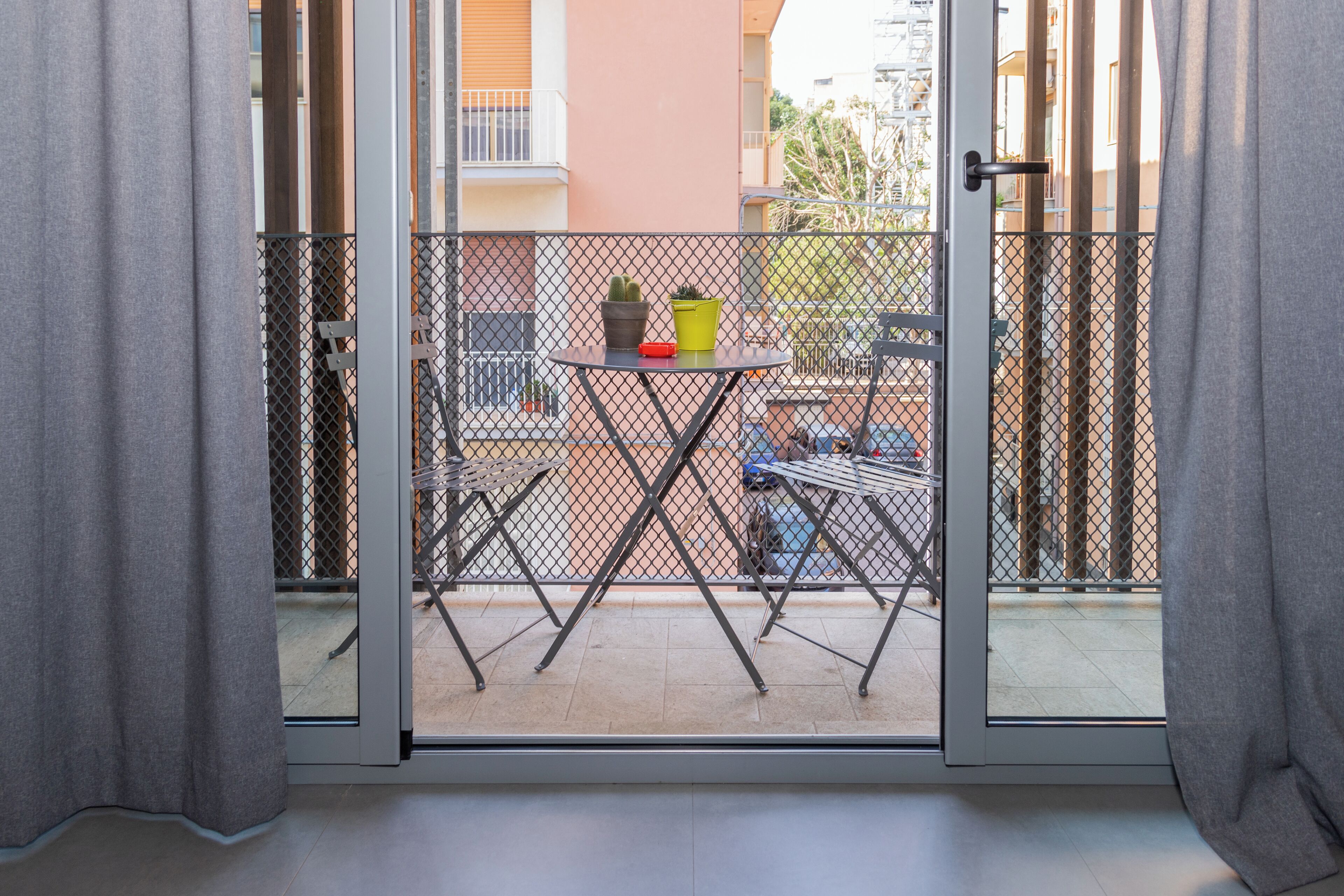 Een balkon met een tafel, stoelen en plantenpotten.